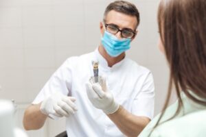 Dentist showing patient a dental implant. 